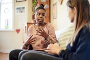 A young woman speaks to her therapist. She is participating in trauma therapy in Towson, MD.
