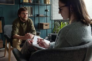 man talks with therapist about social anxiety triggers and how to manage them